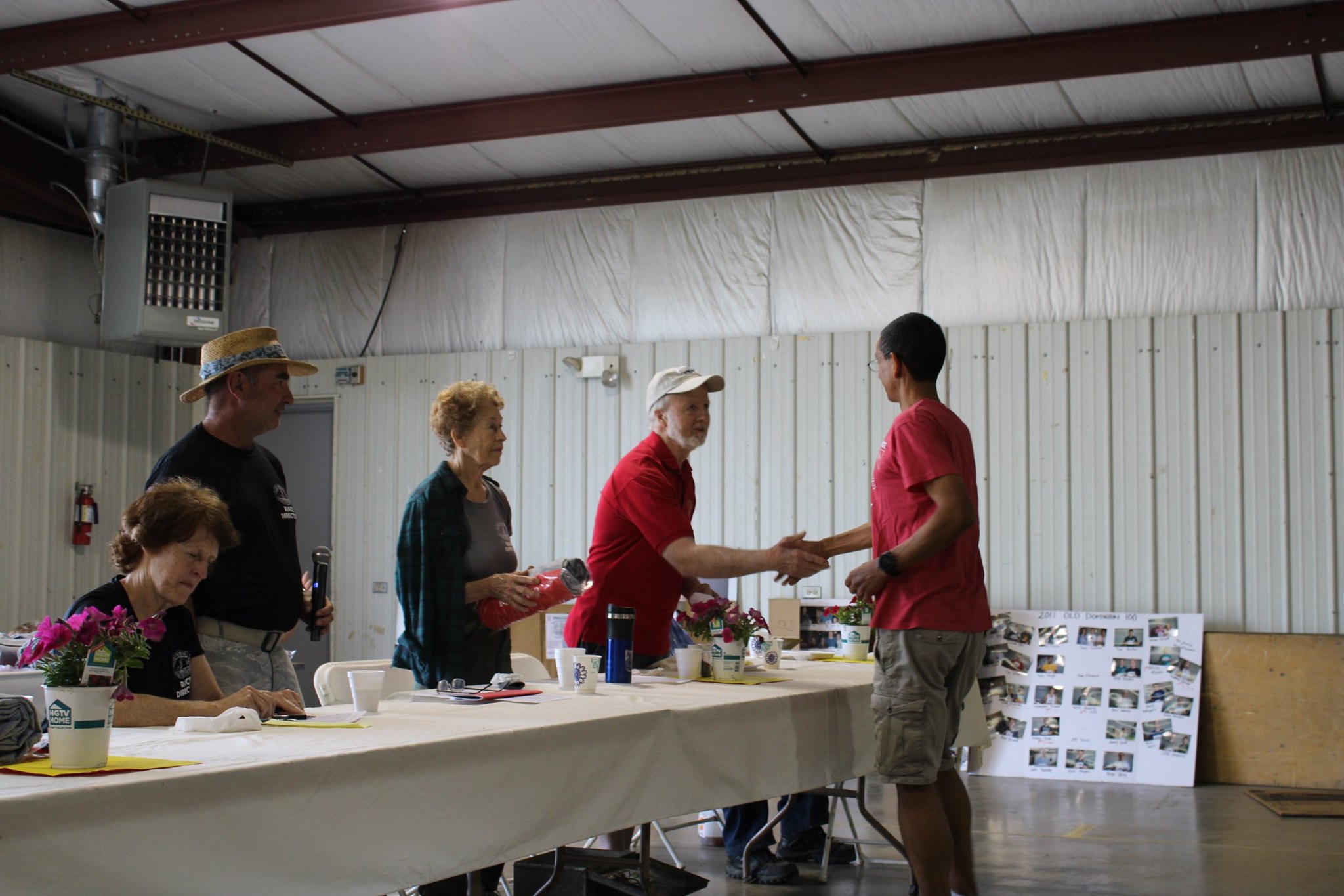Ed Foley, one of the original finisher, holds the record of most OD finishes, shakes hands with Andres Hernandez. Pat Botts 
          stands next to him, Ray and Wynne Waldron, current RDs at the table also.